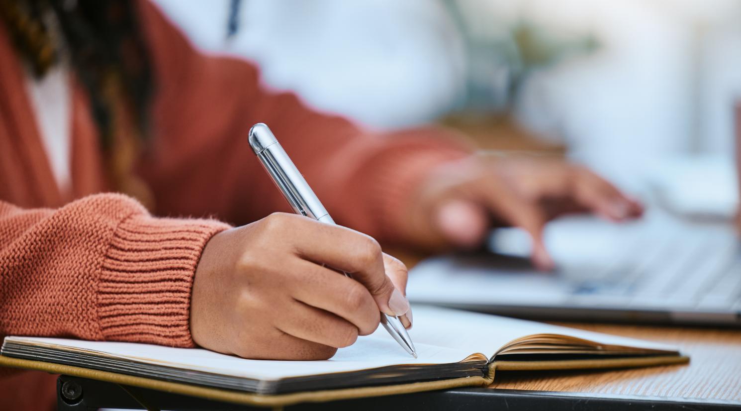 Student, zoom of hand with pen, writing schedule plan.