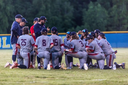 Brenna Hoffer in a huddle with baseball players.