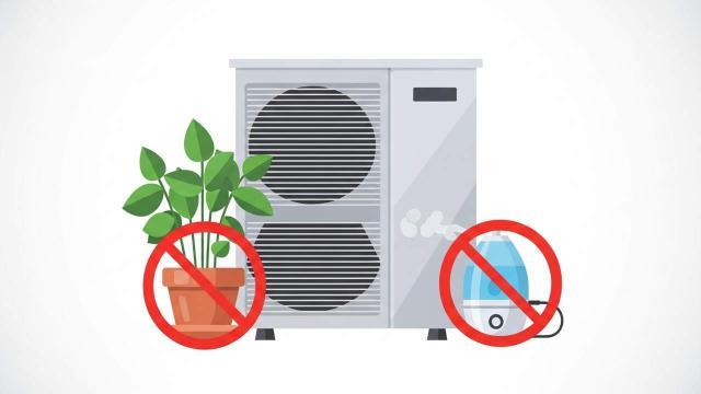 Air conditioning unit with a crossed-out symbol over a potted plant and humidifier, indicating they should not be placed nearby.