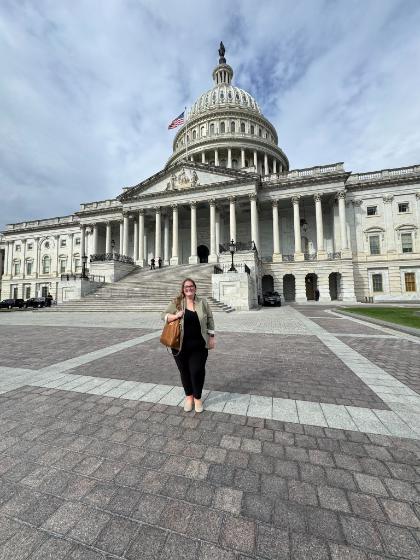 A woman stands smiling in front of the U.S. Capitol building in Washington, D.C.