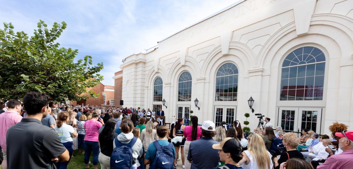 Crowd awaits the Joan Perry Brock Center ribbon cutting. The building is in the background.