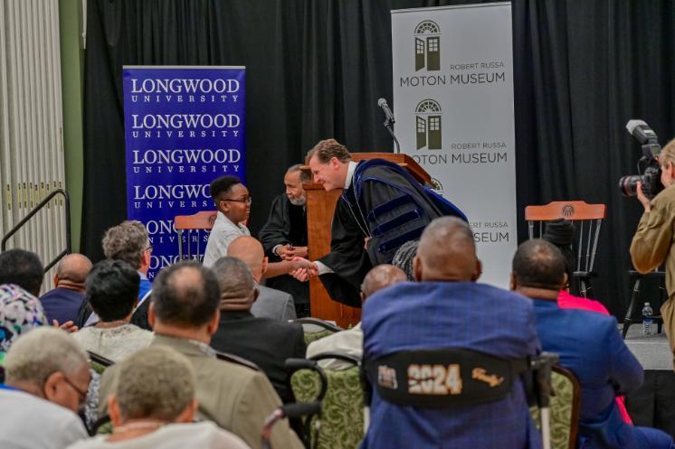 President Reveley shakes 13-year-old Jayden Woodson’s hand as he walked in the place of his grandfather, Vincent Lowell Earley, and uncle, Lawrence Emerson Early.