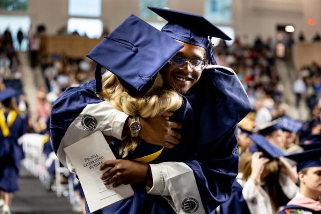 Graduates hug during undergraduate commencement 2024