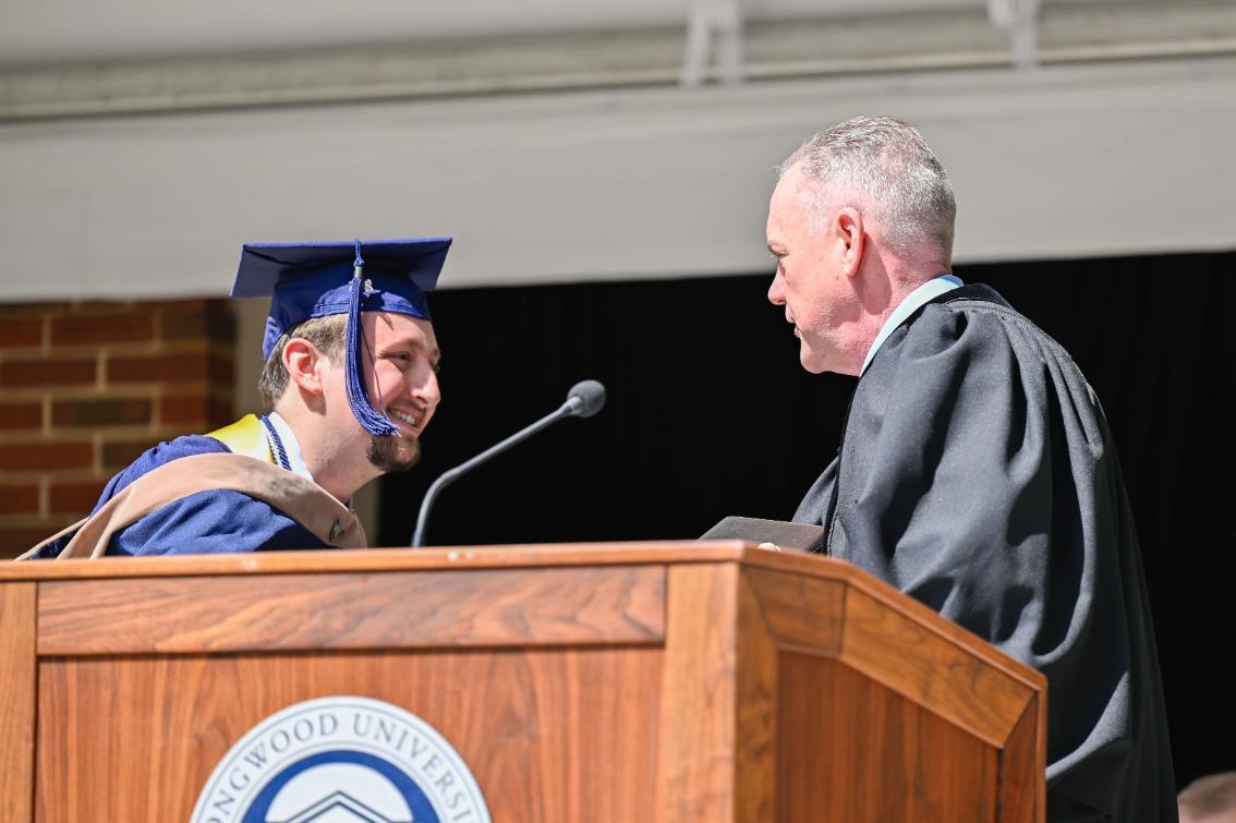 SGA President Neil Miller ’25 hands off the honor and commitment cards signed by the Class of 2025 when they were freshmen to Alumni Association President Chris Tunstall ’88.