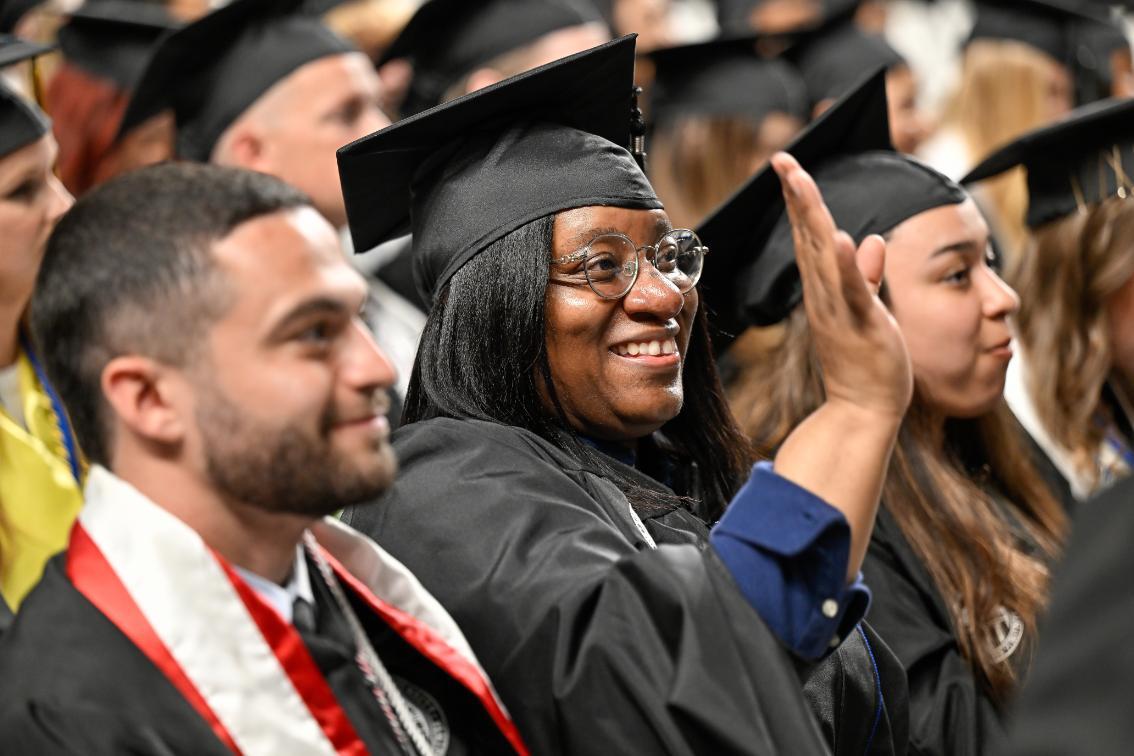 Graduate student waves from her seat during the ceremony