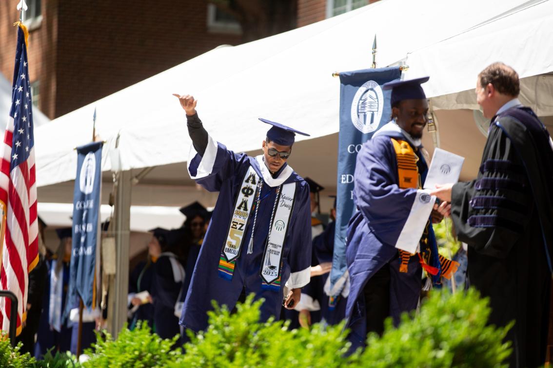 Graduate holds his fist in the air as he crossed the stage