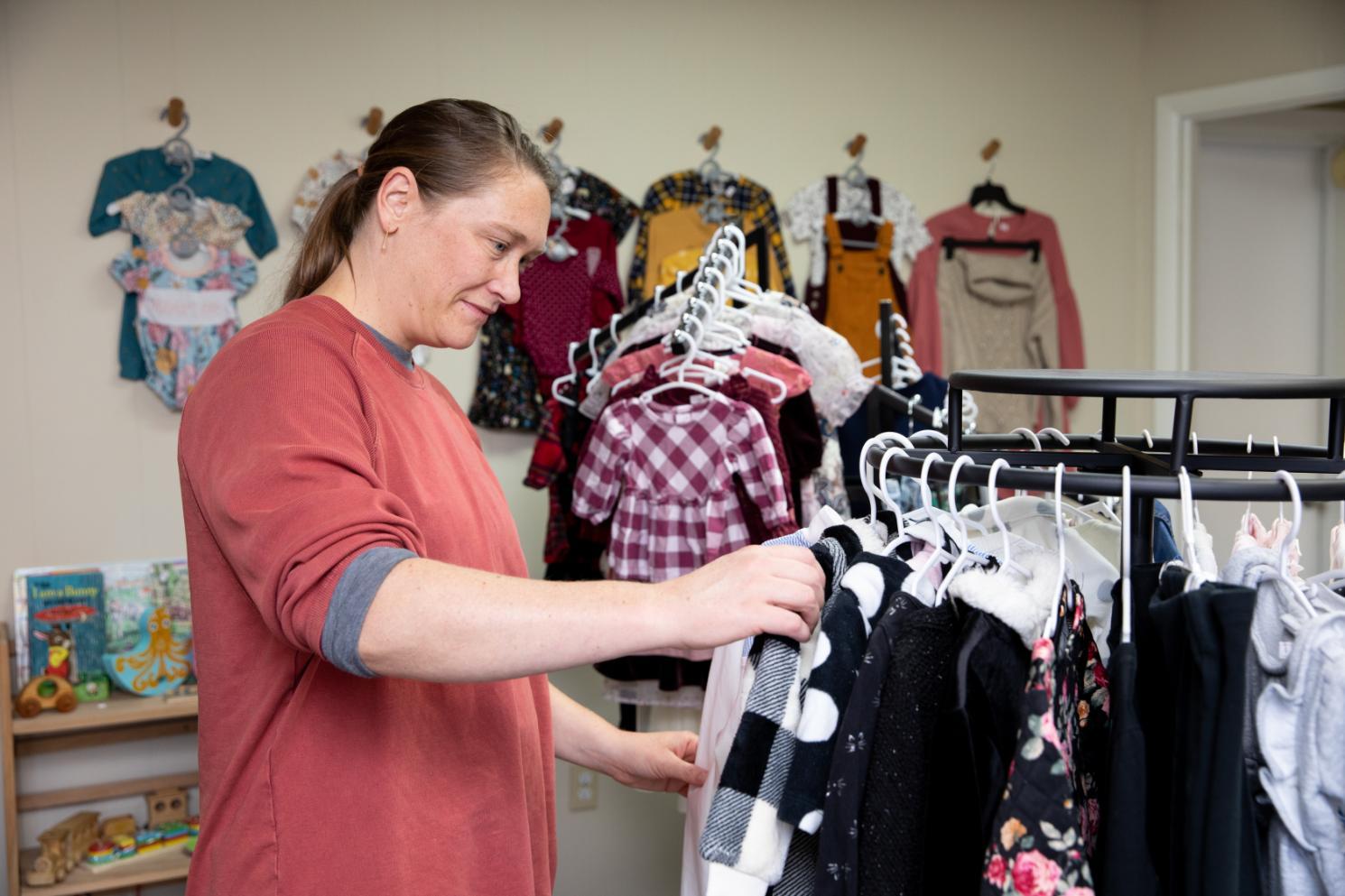 A community member thumbs through the children's coats at A Giving Tree store