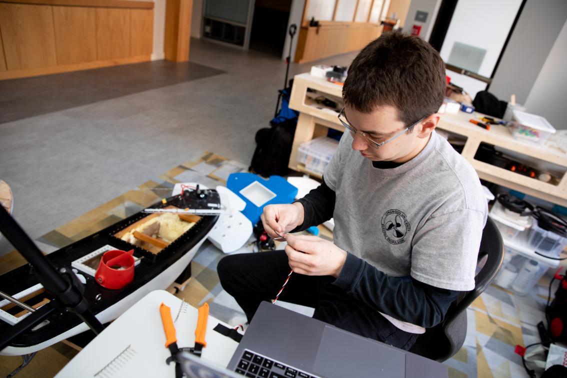 Senior Ben Gettier works on the wiring of his nautical device in Longwood's SEED Innovation Hub. He is sitting in front a computer, connecting three pieces of wire in a spiral formation.