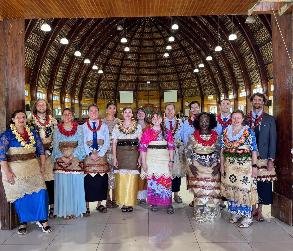 Taylor Bauer '20, M.S. '21 (center in pink) stands at the entrance of a church will fellow Peace Corps volunteers, all wearing traditional Tongan clothing.