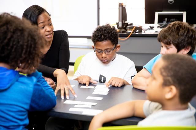 Students huddle around their teacher during Lancer for a Day, and the teacher is explaining the activity they need to complete.